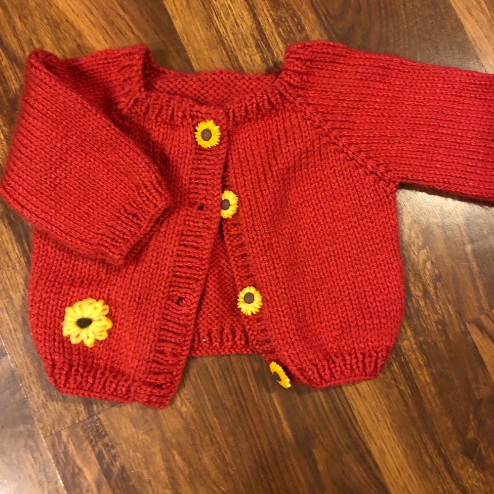 Pink knit cardigan with sunflower buttons.